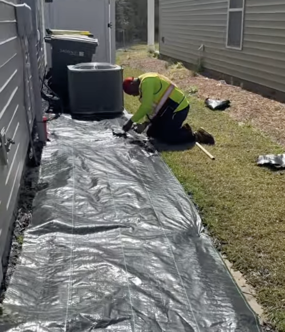 Yard prep and ground cover work along the side of a home