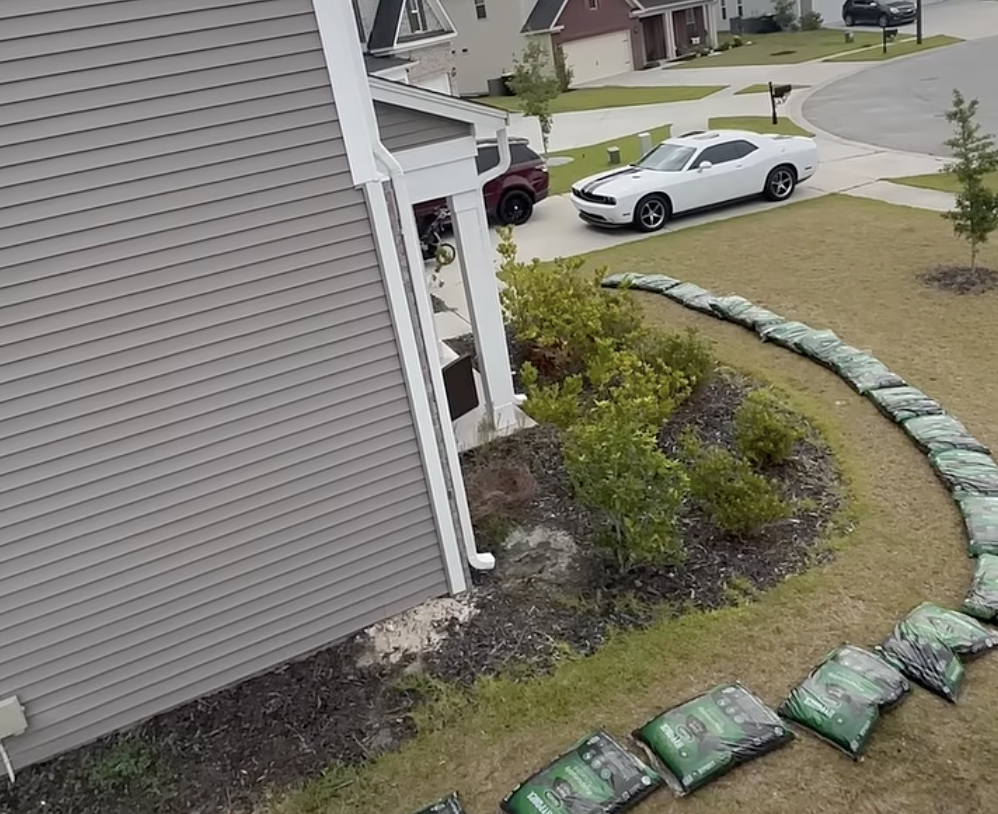 Fresh mulch bags staged around a landscape bed for installation
